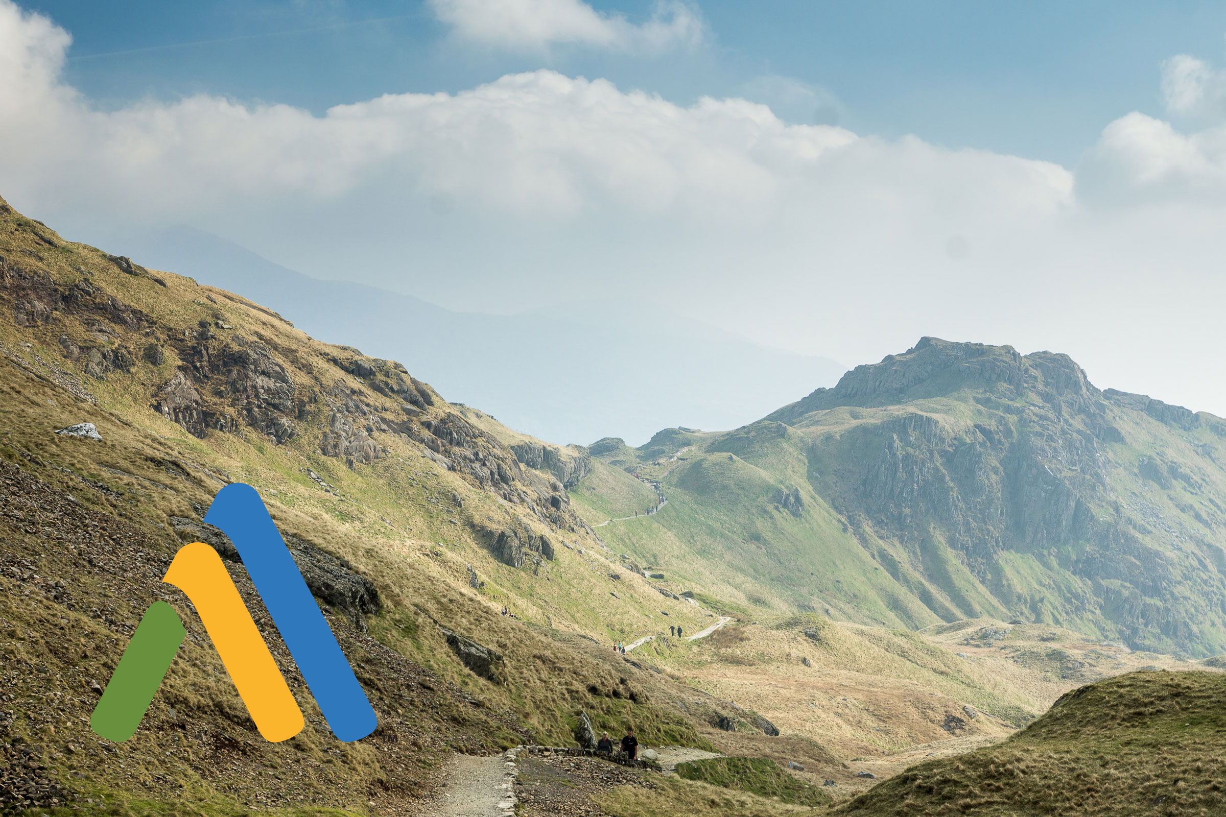 Mountain landscape with hiking trail and logo.
