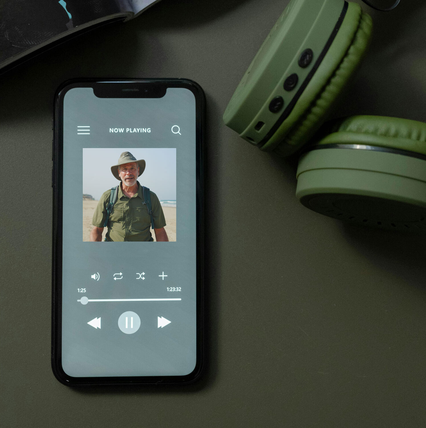 Smartphone displaying podcast beside headphones.