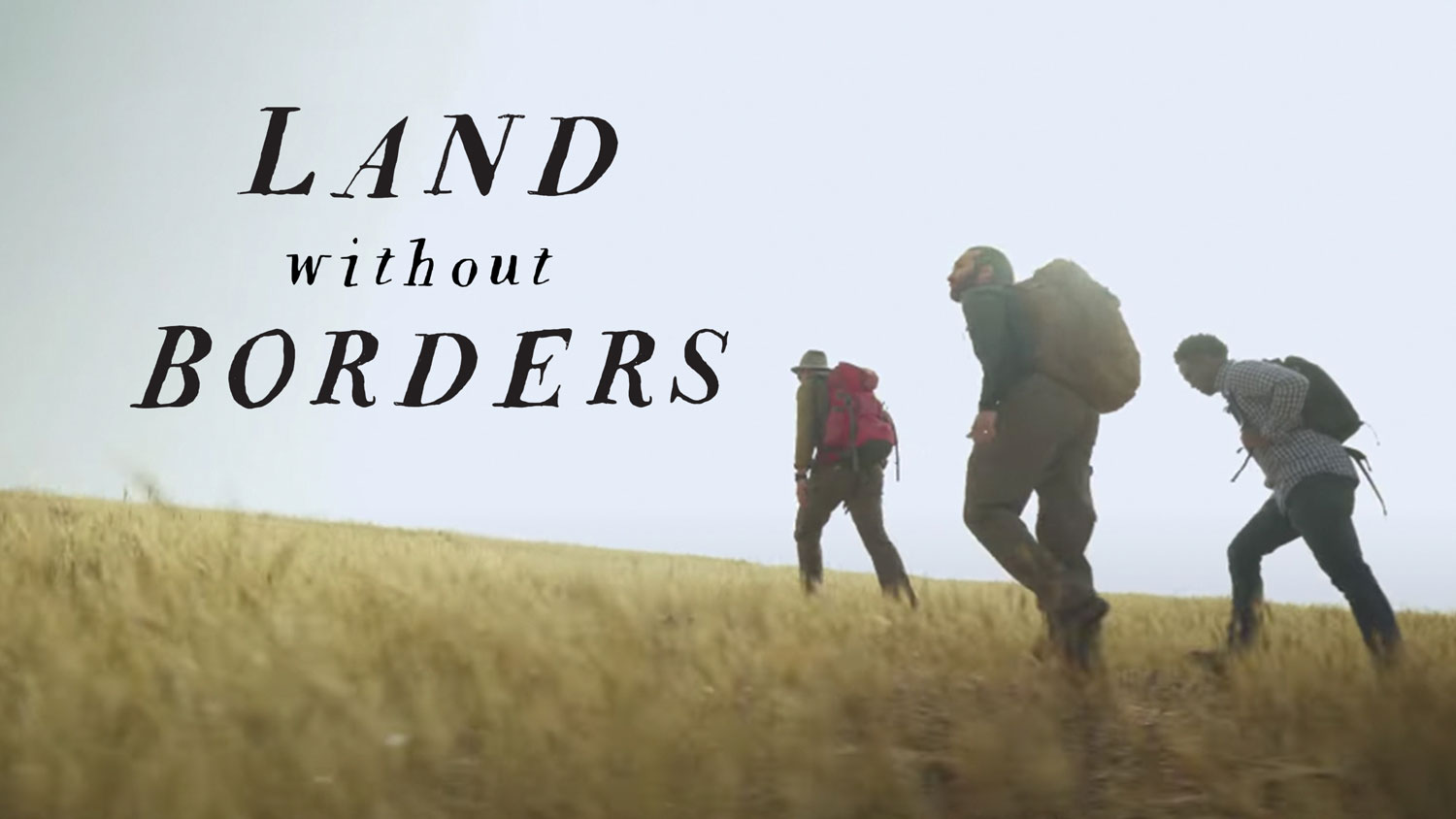 Hikers walking through a wide open field.